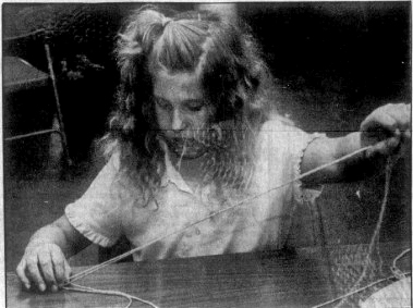 June 13, 1991: Samantha Sherlock strings beads onto strings as she creates a belt. She is participating in Camp Fire Day Camp in Alliance’s Central Park this week.